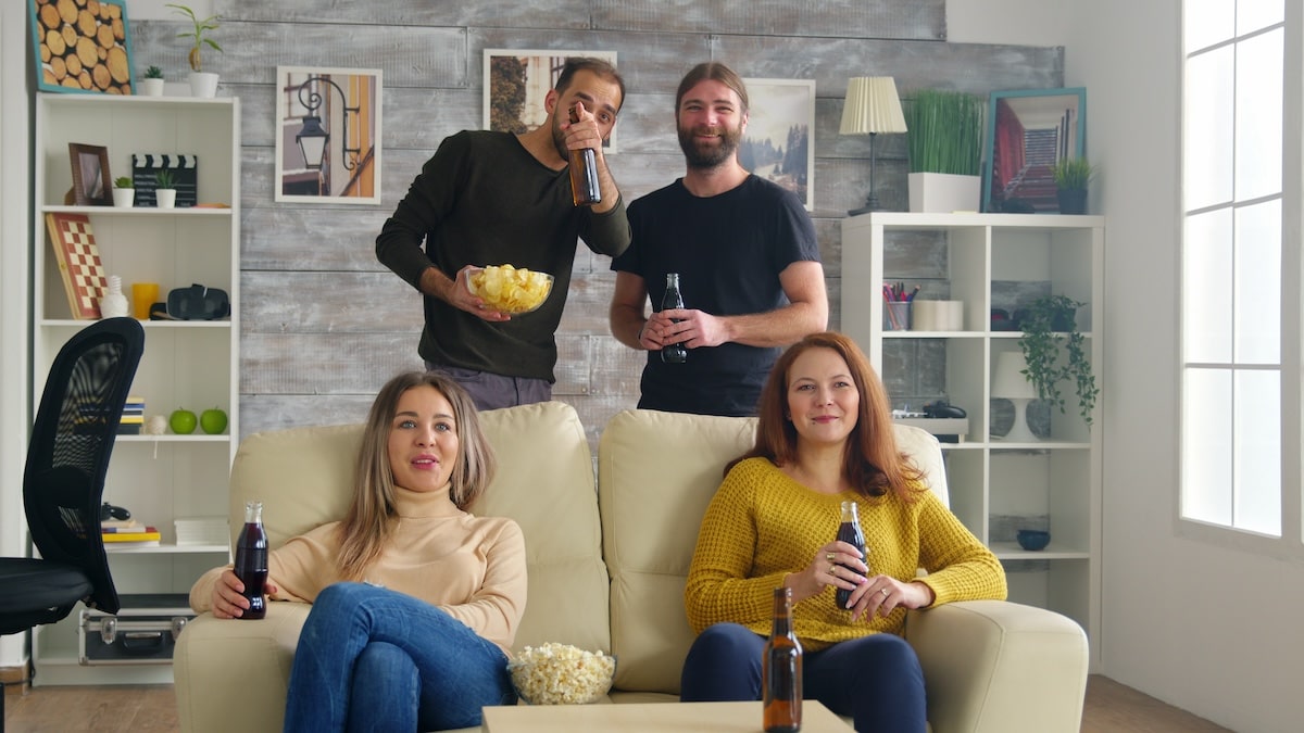 girls sitting on couch eating popcorn while watching tv