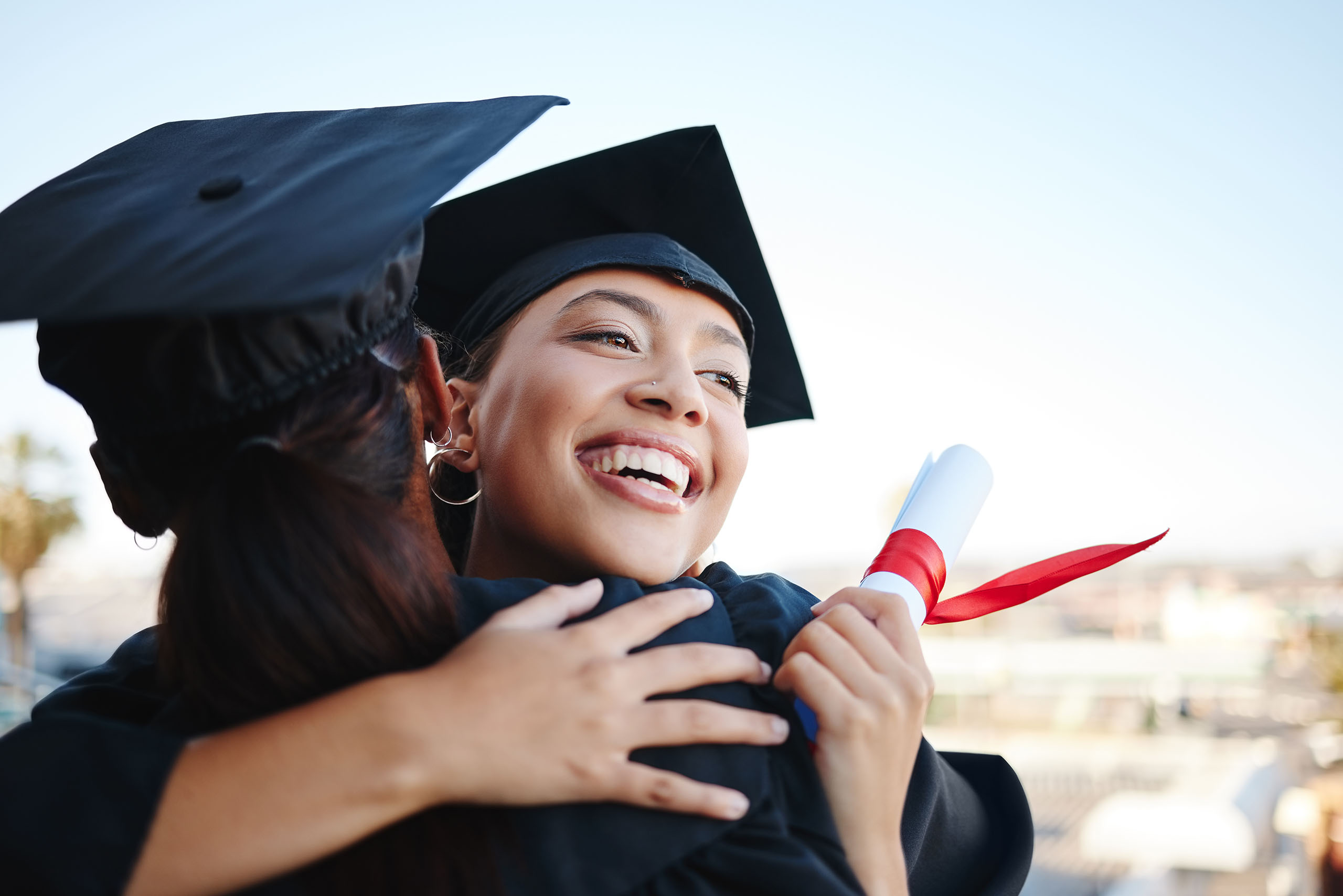 Graduation, education and hug with woman student friends hugging on university campus in celebration of success or qualification. College, graduate and scholarship with a female and friend embracing.
