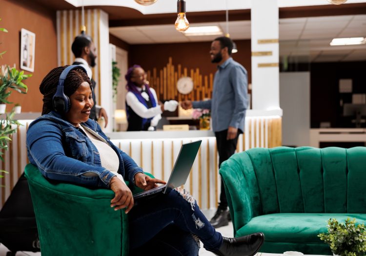 Woman resting in hotel lobby with laptop using free guest wifi